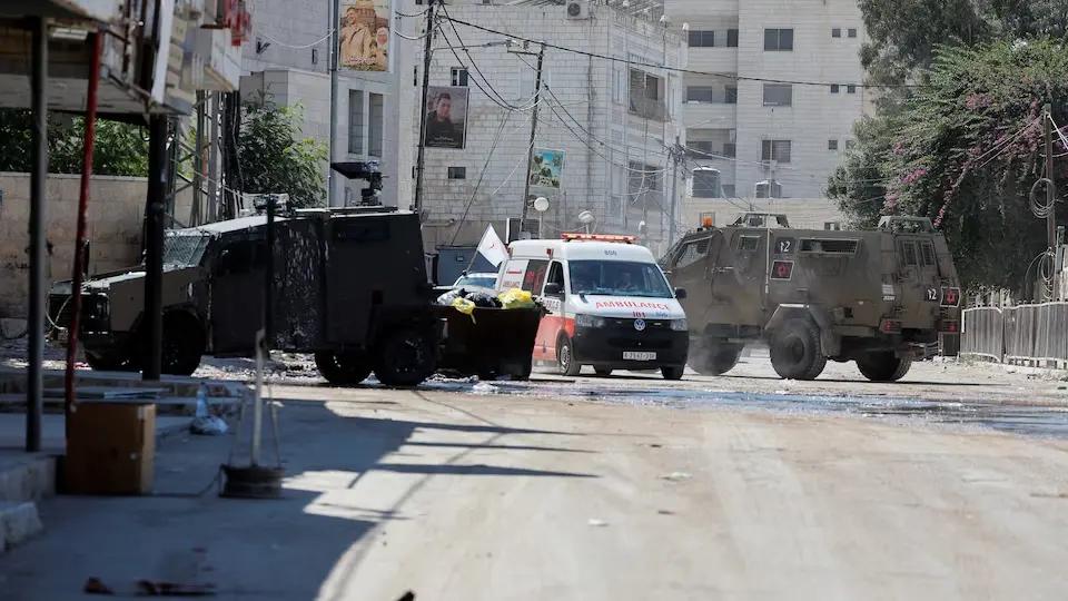 An ambulance drives between Israeli military vehicles which are taking part in a raid, in Jenin, in the West Bank, August 28, 2024.