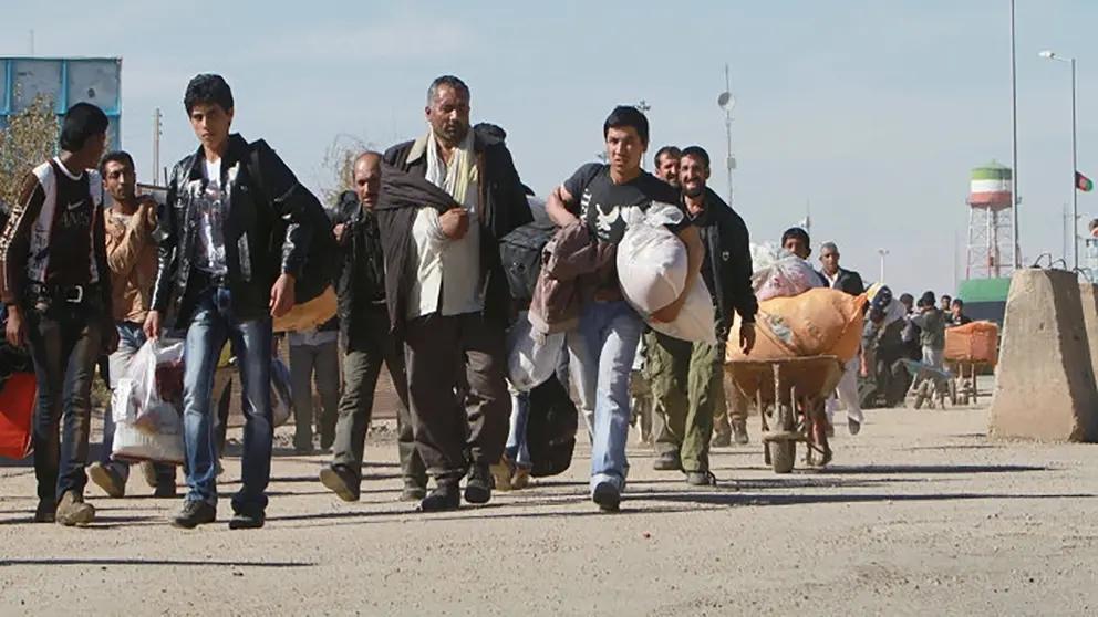 Afghan migrants carry their belongings as they are forced to leave Iran