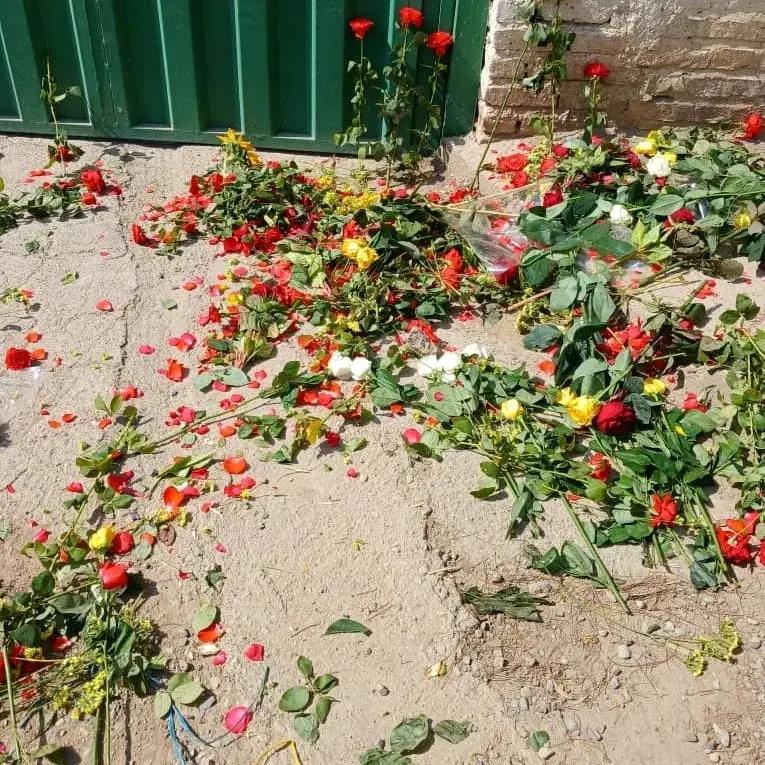 Flowers put outside the closed gate of Khavaran Cemetery